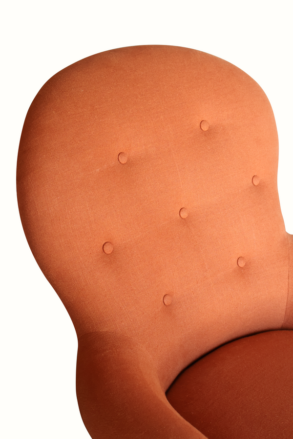 Terracotta armchair backrest with button tufting and a curved upholstered edge