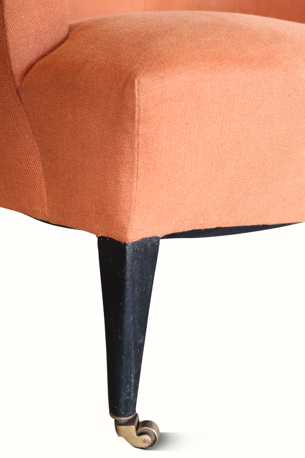 Terracotta upholstered chair with black tapered legs and brass-colored foot