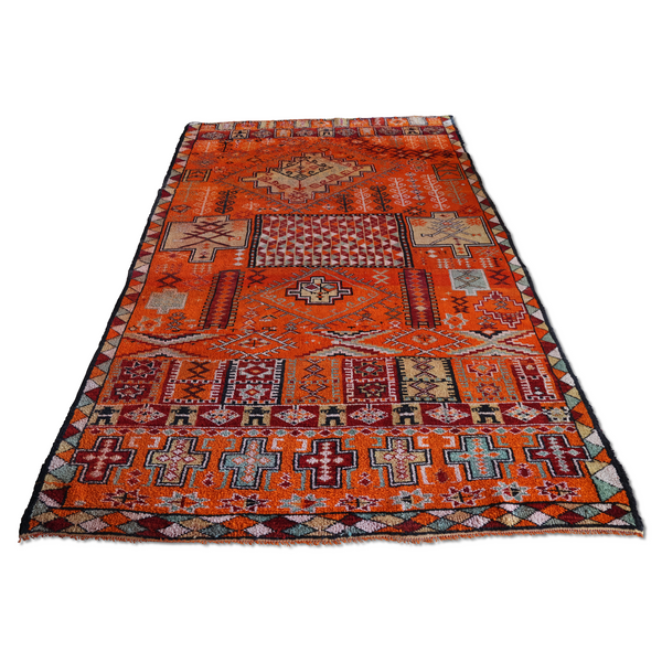 Red Moroccan rug with geometric medallion pattern and navy border, fringed edges