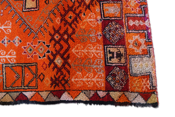 Orange rug with geometric motifs, navy frame, multicolor accents, short fringe