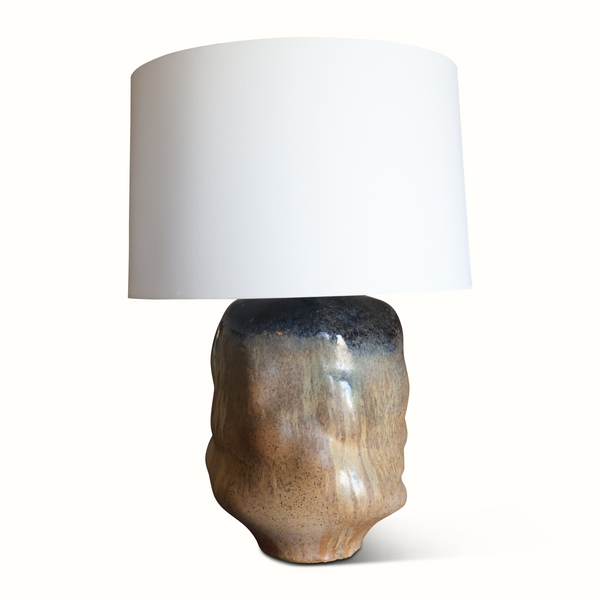 Brown glazed ceramic lamp on table with off-white drum shade