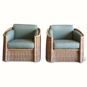 Two woven wicker armchairs with light blue seat cushions, rounded arms and backrests.
