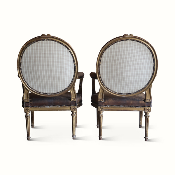 Pair of round-back armchairs with checkered fabric backs, dark seats, and gilt wood trim