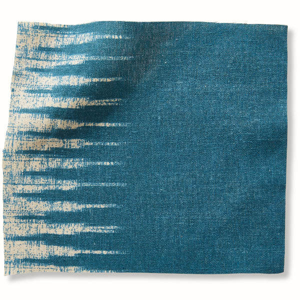 Peacock blue ikat pillow cover with textured striped pattern on left and solid right