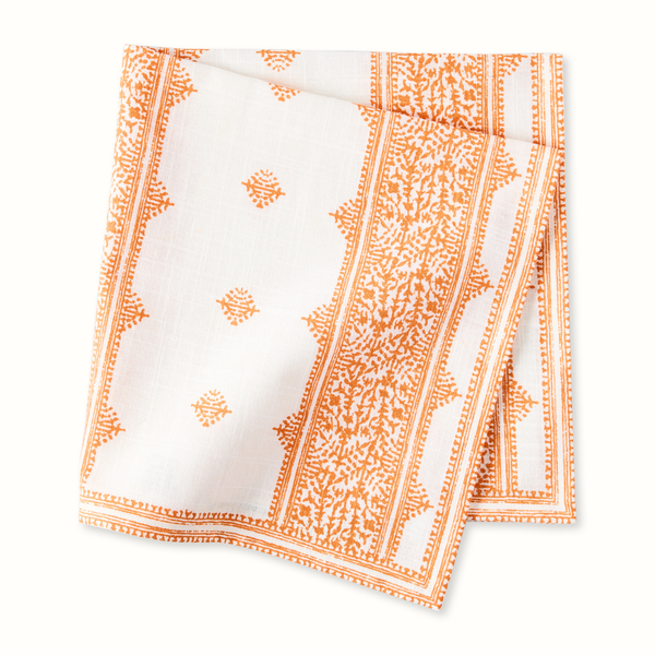 Orange and white printed napkin with border stripes and geometric motifs, folded square