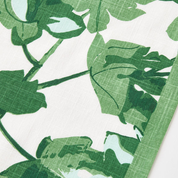 White fabric runner with dense green fig leaf print, close-up