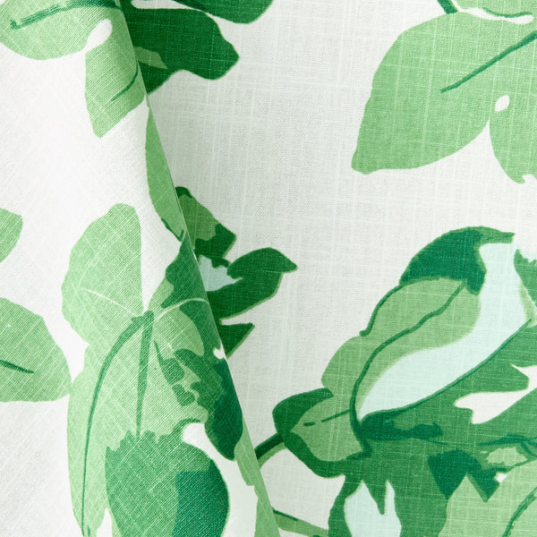 Leaf-printed tablecloth fabric close-up, green leaves on white with woven texture