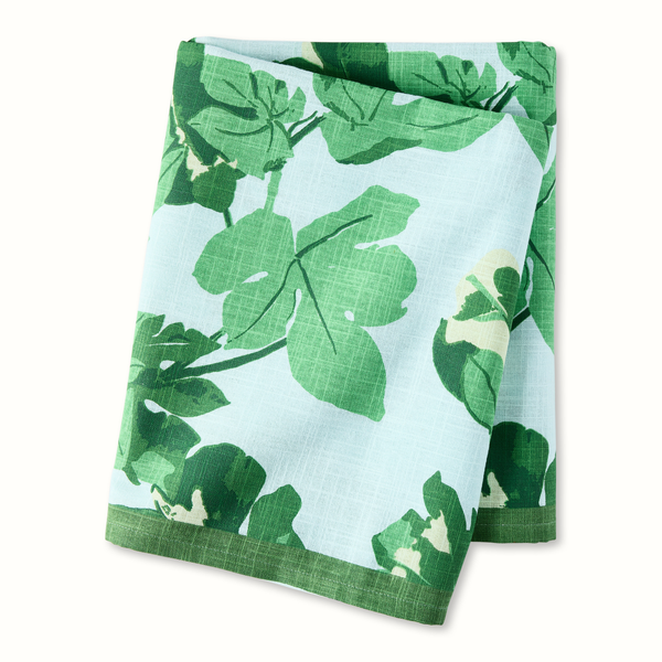 Pale blue tablecloth with green fig leaf pattern, neatly folded.
