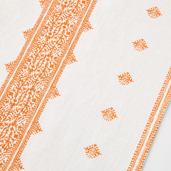 White runner rug with repeating orange medallion and dotted pattern