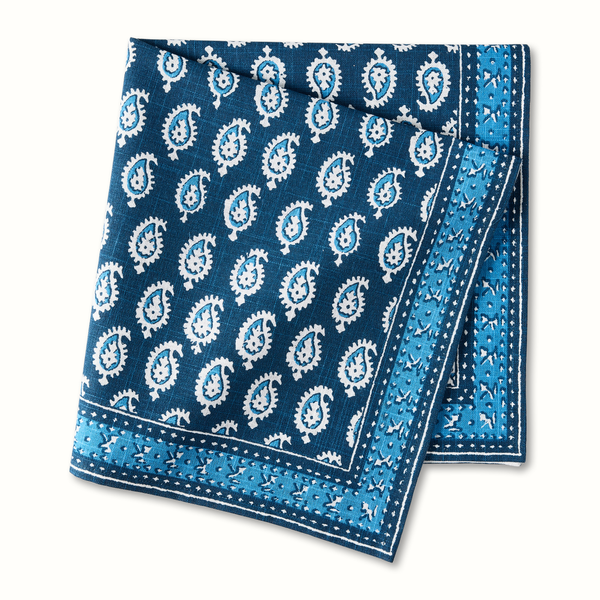 Blue printed cotton napkin with paisley medallion pattern, folded corner edge