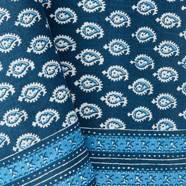 Blue printed tablecloth fabric close-up with circular motifs and striped border