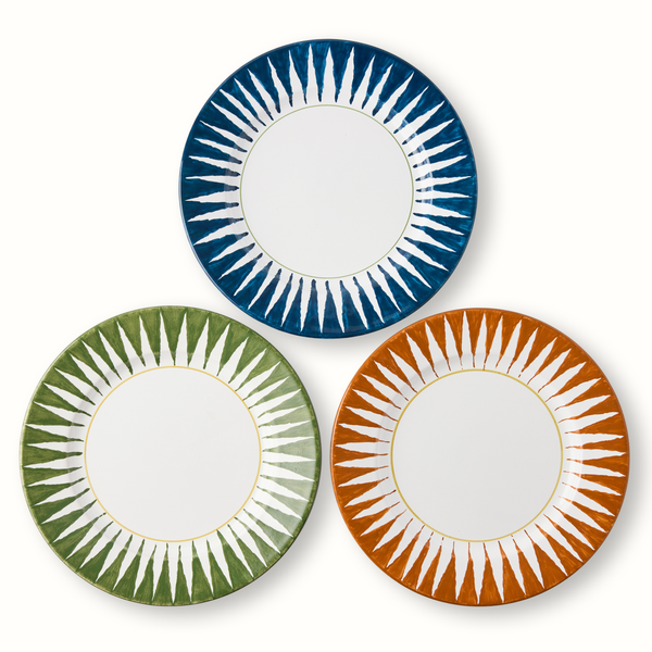 Sunburst dinner plate trio: indigo blue, green, and orange with radial stripe rims