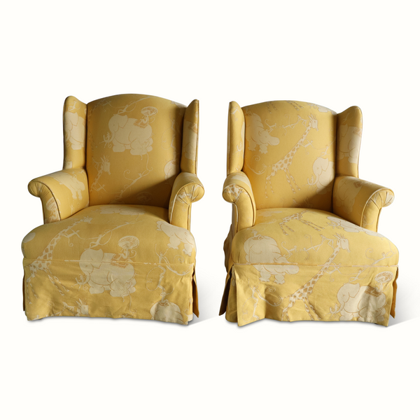 Pair of yellow wingback armchairs, front view with light animal circus print upholstery