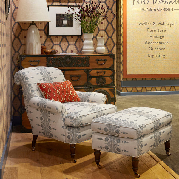 Armchair with light upholstery and blue pattern, in a room setting, rolled arms, caster legs