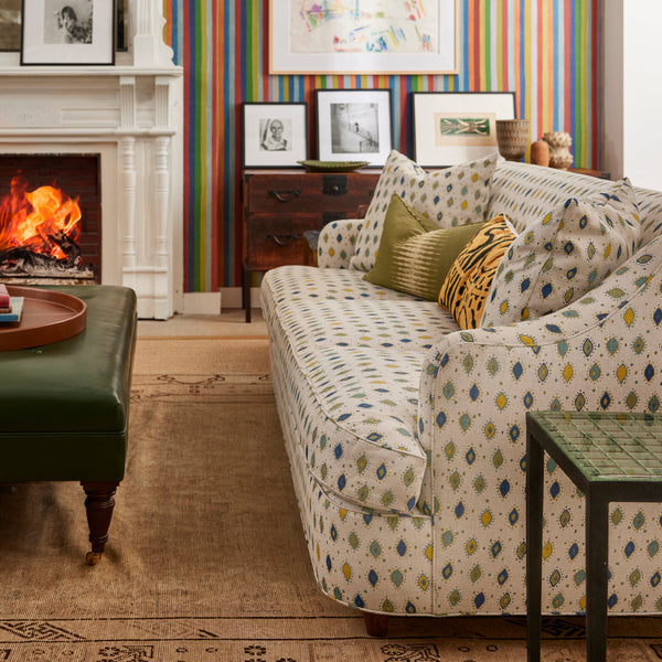 Sofa with patterned upholstery and rolled arms, styled with multiple printed throw pillows.