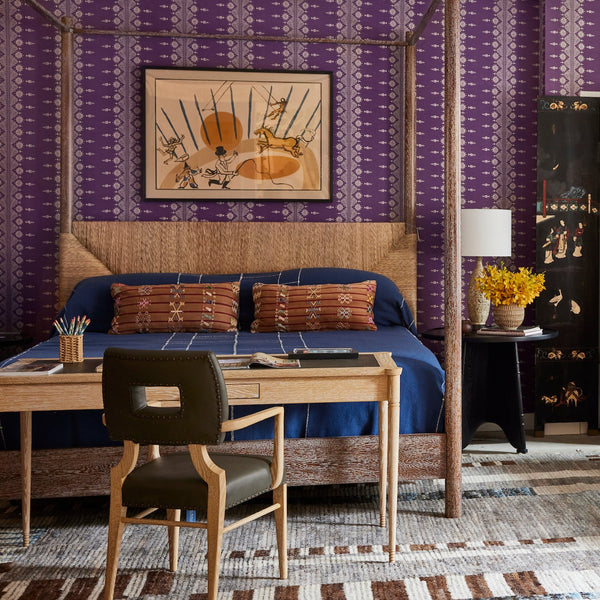 Rattan armchair with woven beige back and seat, shown in a styled bedroom setting