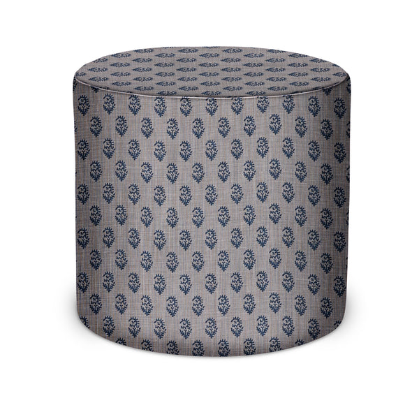 Indoor round upholstered pouf with small indigo repeating pattern on light mist fabric