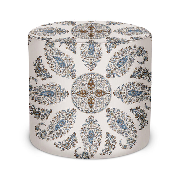 Round upholstered indoor pouf with blue and brown paisley medallion pattern on light fabric