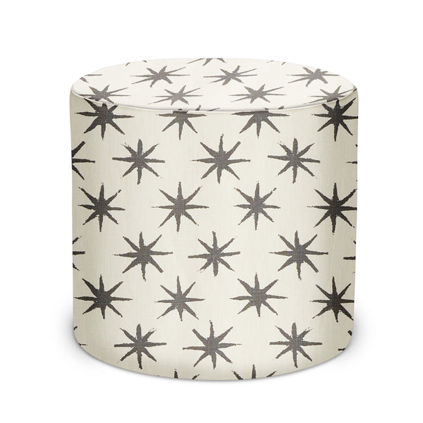 Round indoor pouf with charcoal starburst pattern on off-white fabric