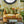 Patterned sofa with three seat cushions and rolled arms, featuring green and tan upholstery.