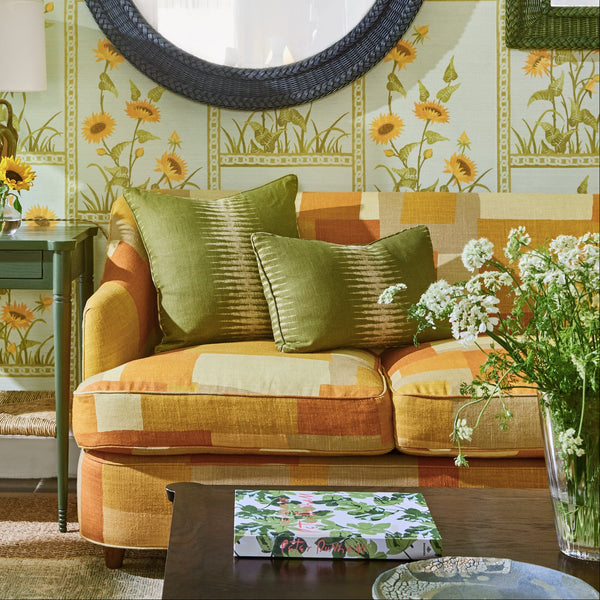 Patterned sofa with three seat cushions and rolled arms, featuring green and tan upholstery.