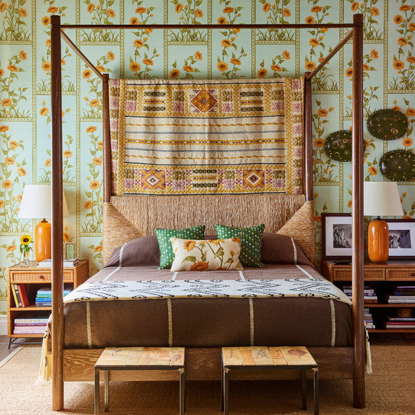 4-poster bed with dark wood posts and woven straw headboard, with patterned bedspread and pillows