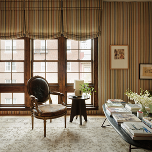 Round-back armchair with dark upholstery, gilded legs, and curved carved wooden arms