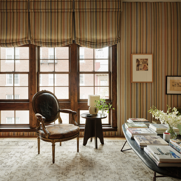 Round-back armchair with dark upholstery, gilded legs, and curved carved wooden arms
