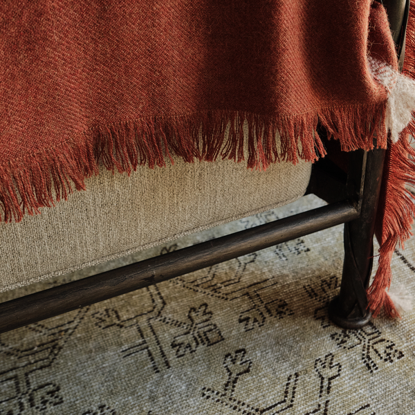 Orange alpaca throw corner with long fringe and white stitch trim