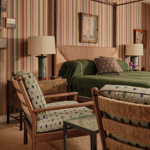 Green bedcover with patterned pillow and folded throw blanket on a bed