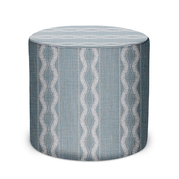 Round upholstered indoor pouf with blue textured fabric and wavy border