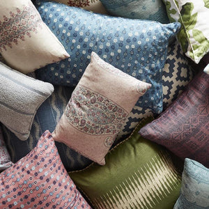 A colorful pile of patterned pillows including stripes, stars, and paisleys.