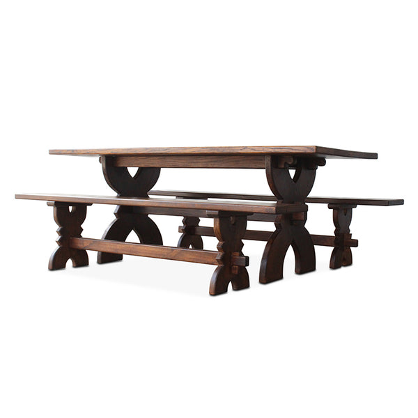 Vintage walnut bench with long plank seat and carved spindle-style trestle ends, angled